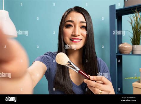 Fashion Blogger Recording A Livestream Tutorial Presenting Makeup Tools And Engaging Her